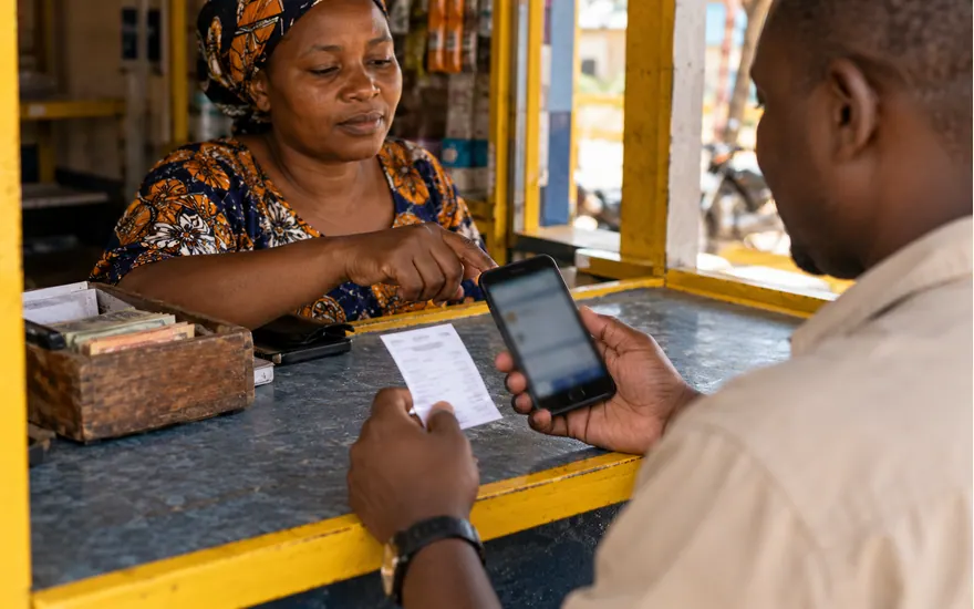 A Tanzanian customer and agent compare the phone and transaction record