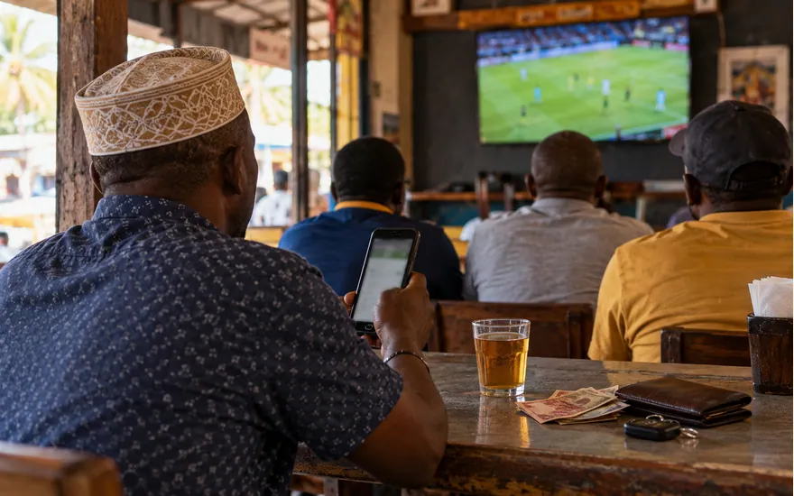 Adults watch a football match in a Tanzanian viewing bar
